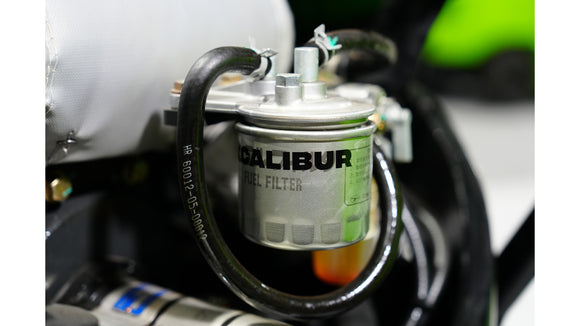Close-up of a Calibur fuel filter installed in an engine, showcasing its metal design and connection hoses.