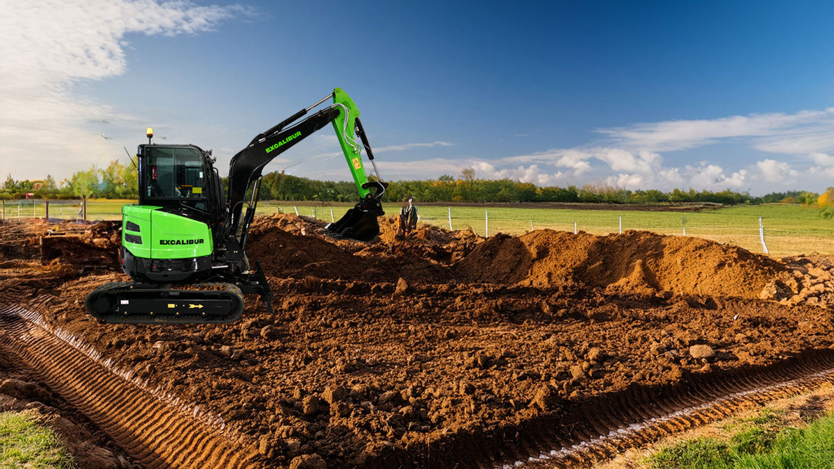 Excavator digging a trench in a construction site with a bright sky and fields in the background.